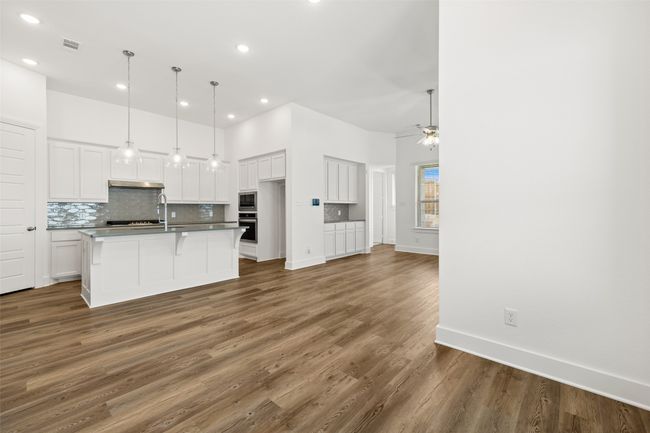 Kitchen featuring white cabinetry, wood finished floors, stainless steel appliances, and tasteful backsplash | Image 5