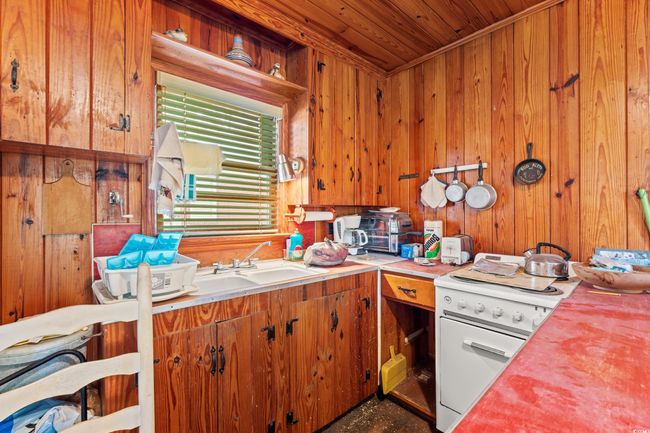 Kitchen with white electric stove, wooden walls, wood ceiling, brown cabinets, and wood counters | Image 18