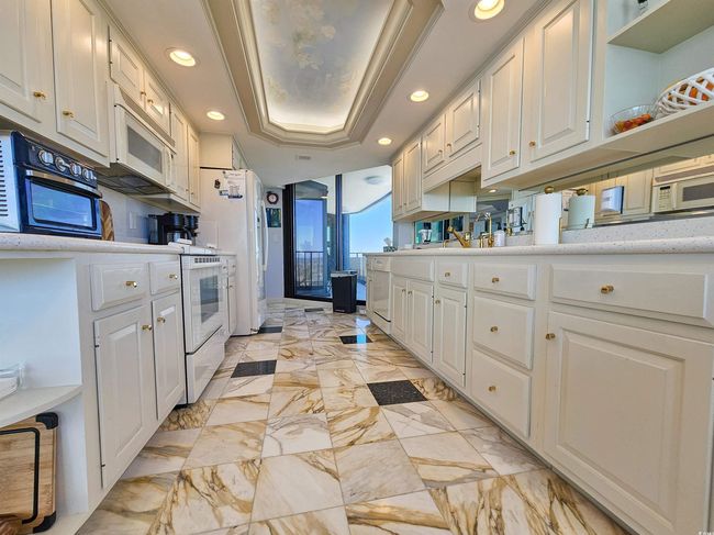 Kitchen featuring light countertops, white cabinetry, and white microwave | Image 14