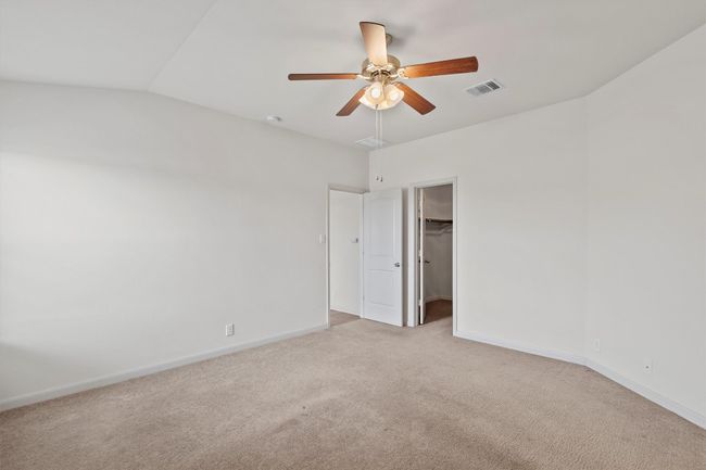 Tucked away from the secondary bedrooms, the private primary suite includes a walk-in closet and ceiling fan for added comfort. | Image 12