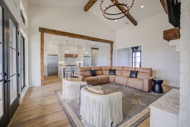 Living area with a chandelier, beam ceiling, high vaulted ceiling, and light wood-style floors | Image 22
