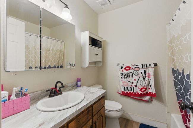 Full bathroom with wood finished floors, vanity, curtained shower, toilet, and visible vents | Image 20