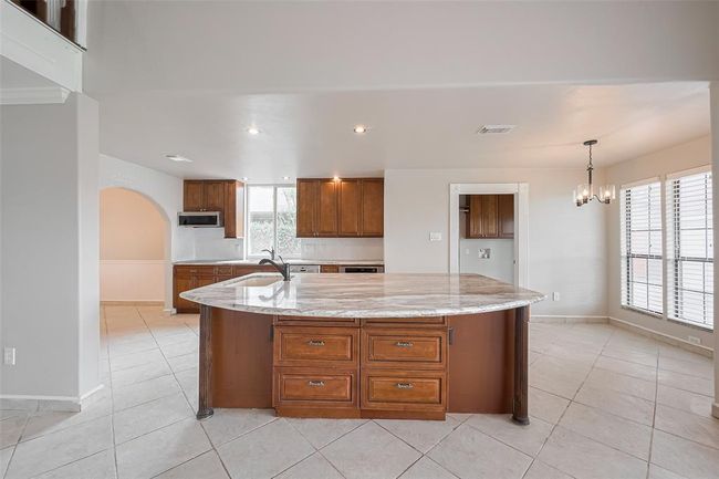The heart of the home features an expansive granite island with ample prep space, rich wood cabinetry, and elegant pendant lighting. This kitchen was designed with both function and flow in mind, offering plenty of room for gathering. | Image 13