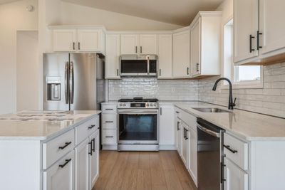 Photo is of the actual home. Welcome to the Crosby! This spacious kitchen features a large center island, quartz countertops, LVP floors, stainless appliances and more. | Image 2