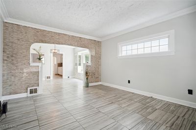 Tiled empty room with a textured ceiling and ornamental molding | Image 2