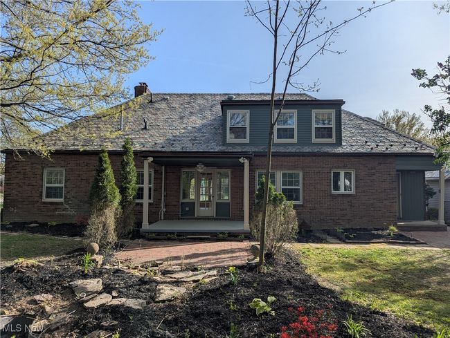 Rear view of house featuring brick siding, a high end roof, a chimney, and a patio area | Image 16