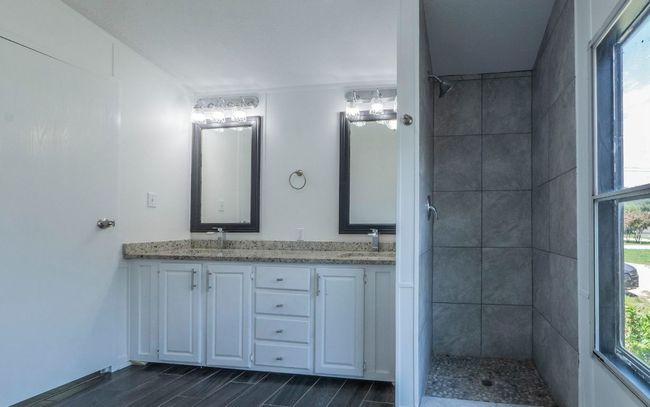 Full bathroom with a tile shower, double vanity, and healthy amount of natural light | Image 9