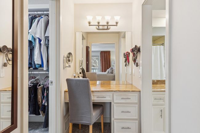 Elegant vanity area with marble-style like countertop, built-in lighting, ample drawer storage, and convenient access to the walk-in closet and primary suite. | Image 16