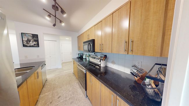 Kitchen with backsplash, dishwasher, a sink, black microwave, and electric range | Image 5