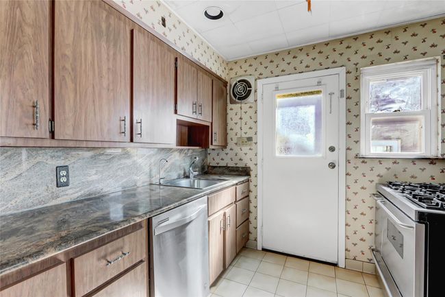 Kitchen with visible vents, a sink, stainless steel dishwasher, wallpapered walls, and white range with gas stovetop | Image 10
