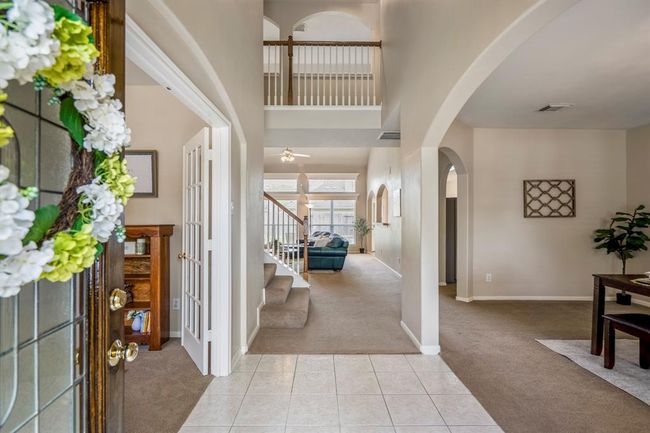 Step inside to a bright and inviting entryway, where French doors to the left open to the study and an arched doorway to the right leads to the formal dining room. Straight ahead, the staircase with a stylish bannister railing overlooks the spacious family room beyond. | Image 4
