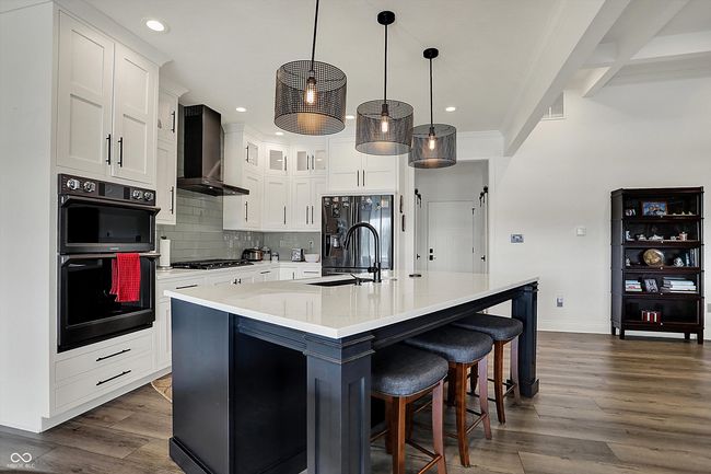 kitchen featuring a sink, black appliances, baseboards, backsplash, and wall chimney exhaust hood | Image 13