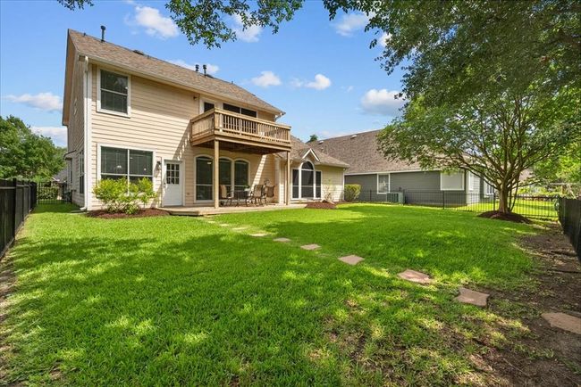 Welcome to your spacious backyard with lush green grass, a balcony and patio area, surrounded by trees and perfect for outdoor gatherings and relaxing. | Image 35