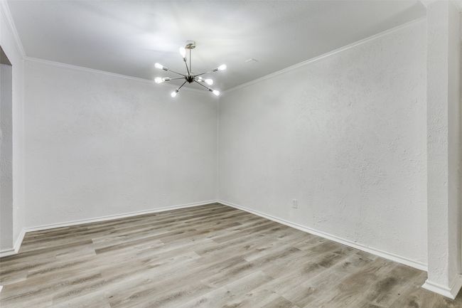 Unfurnished room with baseboards, wood finished floors, a notable chandelier, and crown molding | Image 13
