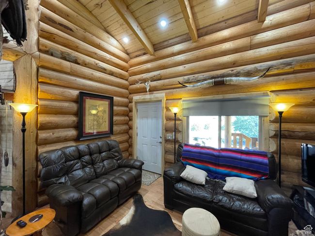 Living area featuring lofted ceiling with beams, wood finished floors, rustic walls, and wooden ceiling | Image 70