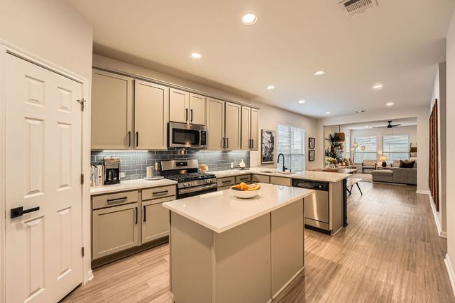 Kitchen with gray cabinets, a peninsula, a center island, appliances with stainless steel finishes, and a sink | Image 11