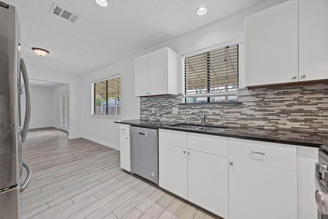 Kitchen with dark countertops, visible vents, a sink, a textured ceiling, and appliances with stainless steel finishes | Image 13