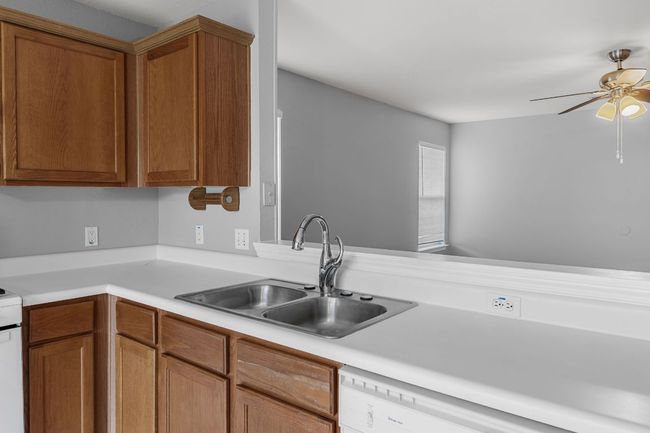 Kitchen featuring ceiling fan, light countertops, brown cabinetry, tile floor, and white appliances | Image 9