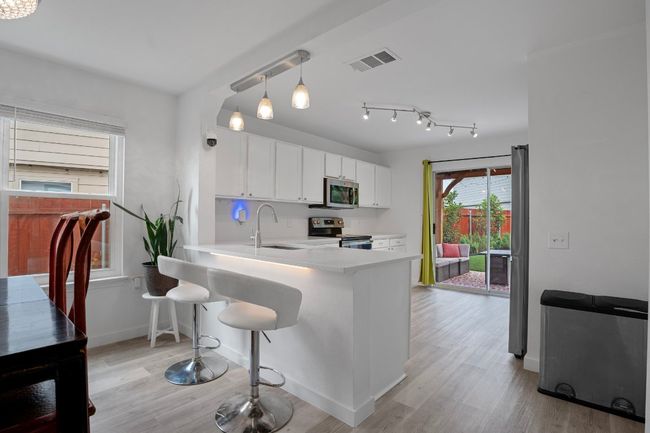 Kitchen featuring appliances with stainless steel finishes, light countertops, white cabinets, and light wood-style flooring | Image 7