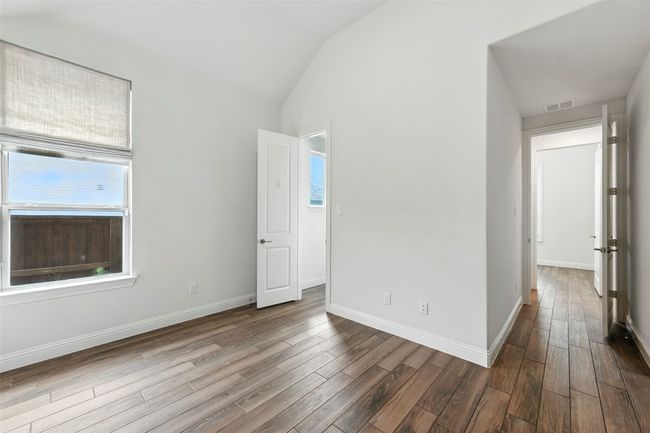 Unfurnished bedroom featuring multiple windows, lofted ceiling, and tile floors | Image 29