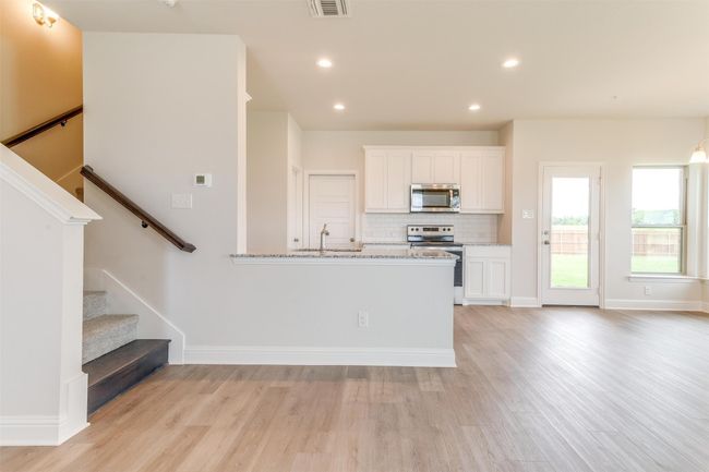 Kitchen featuring white cabinetry, stainless steel appliances, sink, and light stone counters | Image 7