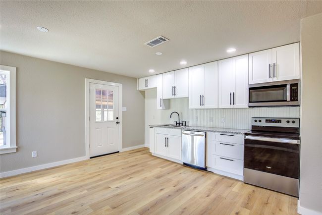 Kitchen with visible vents, a sink, light stone countertops, baseboards, and appliances with stainless steel finishes | Image 8