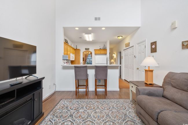 Living area featuring wood finished floors, a towering ceiling, and baseboards | Image 10