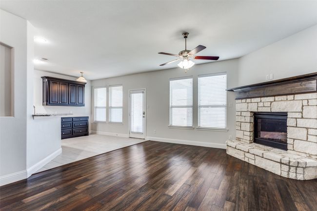Unfurnished living room featuring a stone fireplace, ceiling fan, and hardwood / wood-style flooring | Image 7