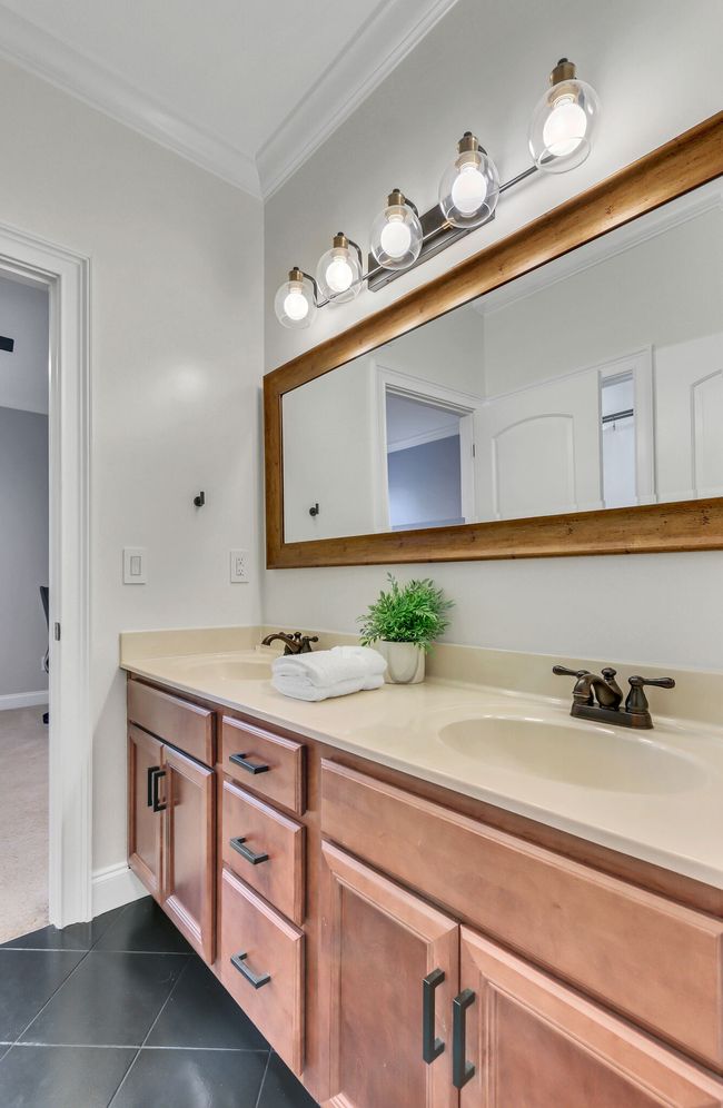 This Jack and Jill bath with double sink vanity serves two guest rooms. Tiled flooring, soft close drawers and crown molding. There is a separate shower room. | Image 39