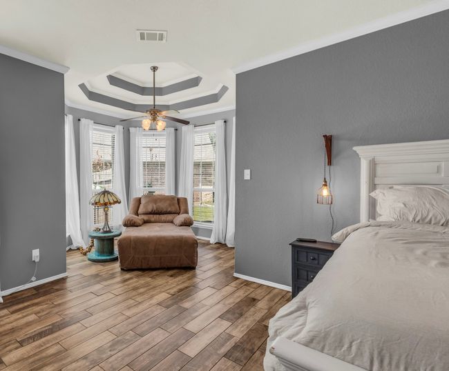 Bedroom with a tray ceiling, crown molding, and ceiling fan | Image 8