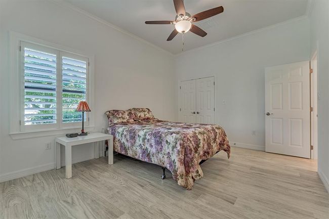 A third bedroom on the first floor offers a comfortable retreat for guests, featuring a full en-suite bath, a double-door closet, and custom wood shutters that provide both privacy and adjustable light control. | Image 29