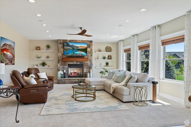 Carpeted living area with built in features, a fireplace, baseboards, recessed lighting, and a ceiling fan | Image 9