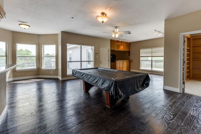 Game room featuring ceiling fan, baseboards, and dark wood-style flooring | Image 12
