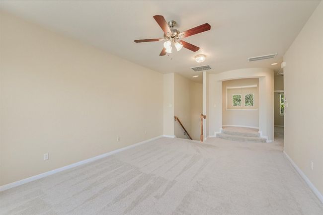 Unfurnished room with light carpet, arched walkways, and a ceiling fan | Image 10