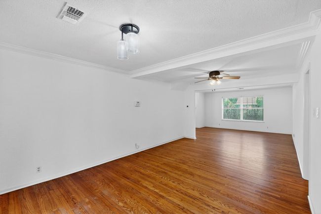 Empty room with wood finished floors, a textured ceiling, a ceiling fan, and crown molding | Image 5