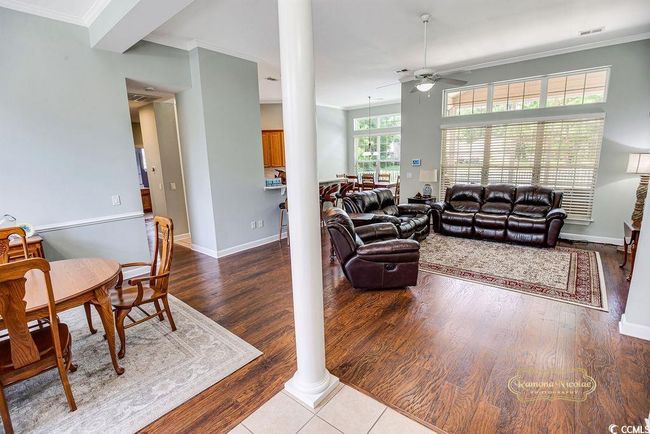 Living room with ceiling fan, ornamental molding, wood finished floors, and decorative columns | Image 9