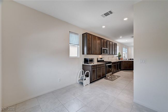 Kitchen with stainless steel appliances, dark brown cabinetry, light countertops, baseboards, and recessed lighting | Image 18