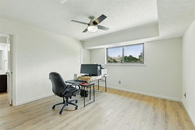 The fifth bedroom has vinyl plank floors (2016), walk-in closet, tray ceiling and an updated ceiling fan. | Image 30