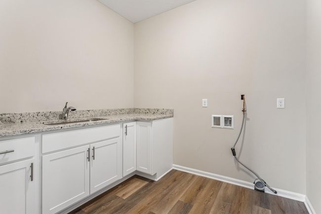 A surprisingly large laundry room with sink, granit countertops and cabinetry. So much room to add shelving or upper cabinets for storage and organization! | Image 11