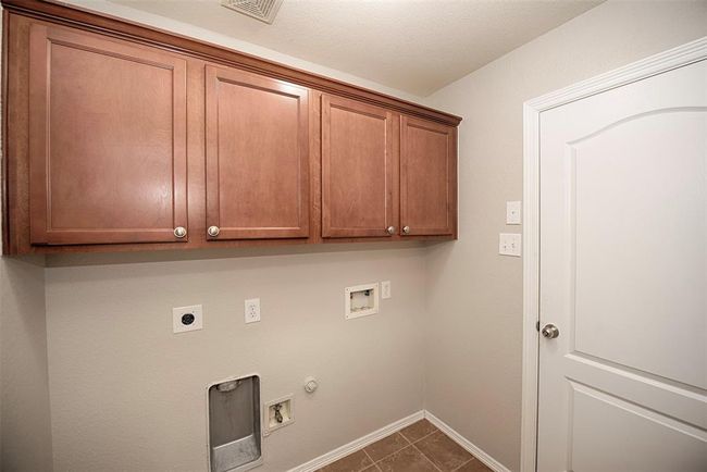At the end of the kitchen and access to the garage is a wonderful utility room with built in cabinetry for storing all of your laundry and household cleaning necessities. | Image 28