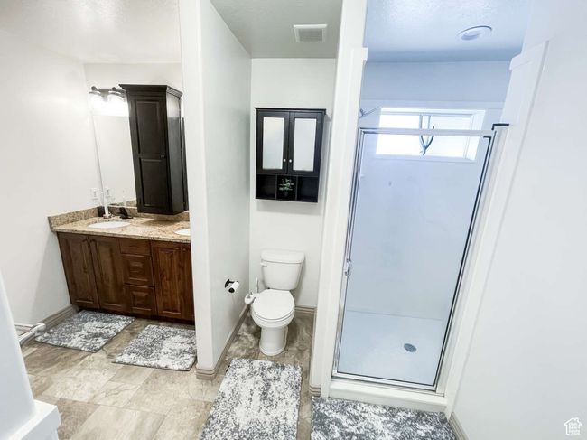 Bathroom with double vanity, a shower stall, toilet, and baseboards | Image 11
