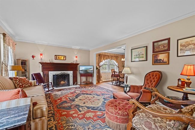 Living area with a lit fireplace, crown molding, and wood finished floors | Image 14