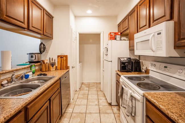 Kitchen with white appliances, brown cabinets, light tile patterned floors, light countertops, and recessed lighting | Image 4