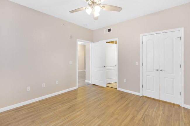 Primary bedroom with walk-in closet, attached bathroom, light wood finished floors, baseboards, and new ceiling fan, and new blinds. | Image 12