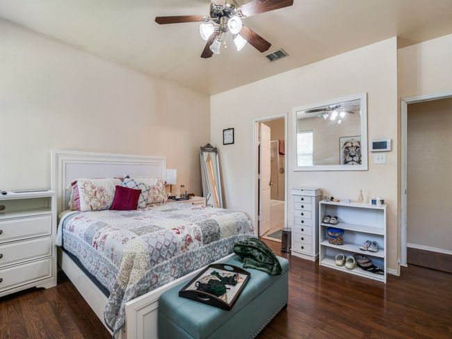 Bedroom with dark wood-style floors, baseboards, a ceiling fan, and visible vents | Image 19