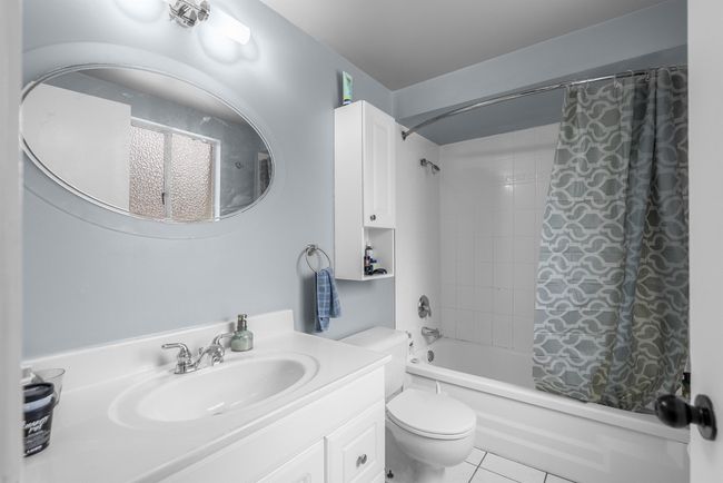 Full bathroom featuring shower / bath combination with curtain, tile patterned floors, vanity, and toilet | Image 18