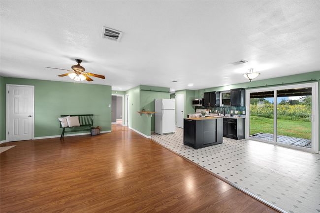 Kitchen featuring freestanding refrigerator, stainless steel microwave, light wood finished floors, a ceiling fan, and light countertops | Image 5