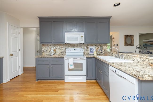 Kitchen with white appliances, gray cabinets, a peninsula, light wood-style flooring, and tasteful backsplash | Image 15