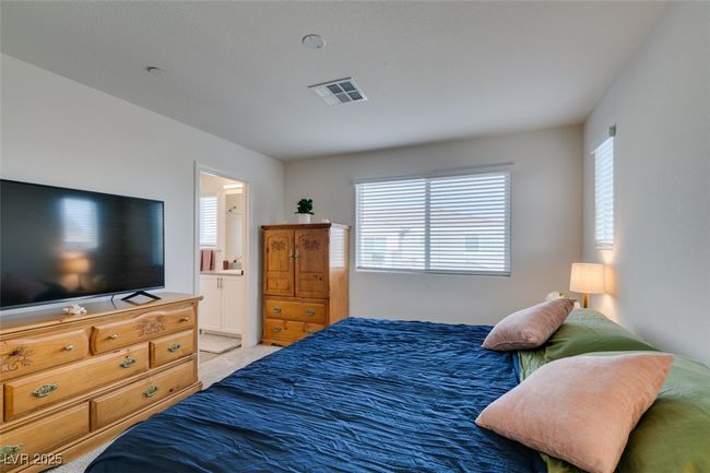 Bedroom with light colored carpet, visible vents, and connected bathroom | Image 23