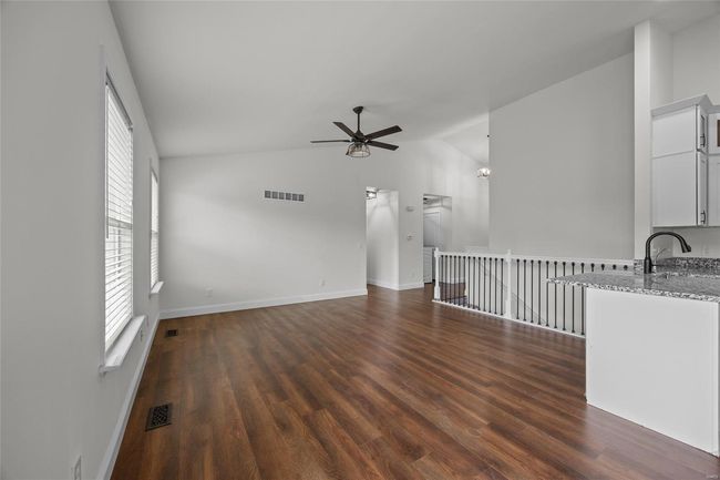 Unfurnished living room featuring vaulted ceiling, ceiling fan, dark wood-type flooring, and visible vents | Image 24